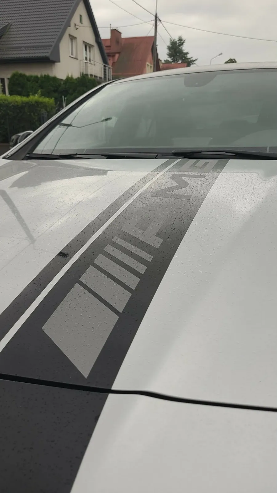 Zbliżenie na napis AMG z folii na masce Mercedesa CLA45